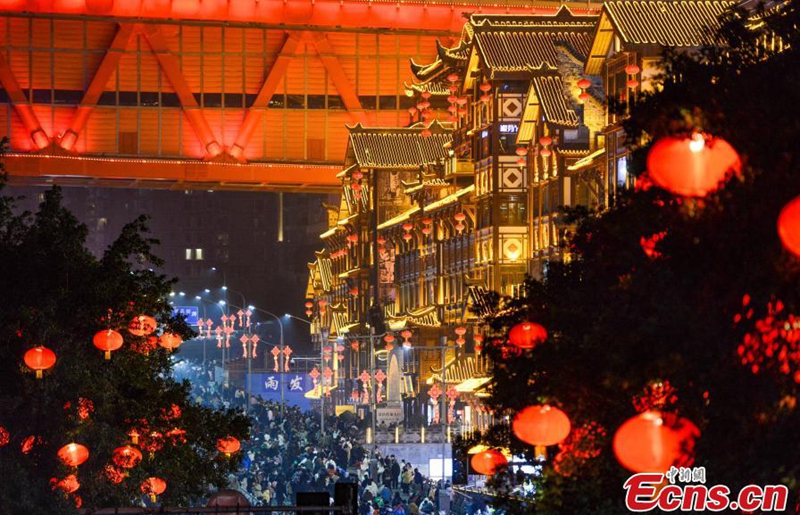 Tourists visit Hongya Cave in Chongqing at night, Jan. 26, 2023. Hongya Cave, formerly known as Hongya Gate, is one of the city gates of ancient Chongqing. Despite the name, this destination isn't really a cave—it's a commercial area. From the bottom, Hongya Cave resembles a series of wooden structures trying to cling to the side of a cliff. (Photo: China News Service/He Penglei) 
