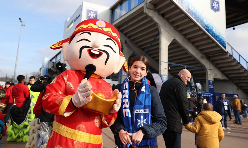 An Auxerre fan poses with a performer dressed up as god of fortune outside the Abbe Deschamps Stadium of Auxerre club before a French Ligue 1 match between Auxerre and Montpellier as part of the Day of China activites to celebrate the Chinese Lunar New Year in Auxerre, France, Jan. 29, 2023.(Photo: Xinhua)