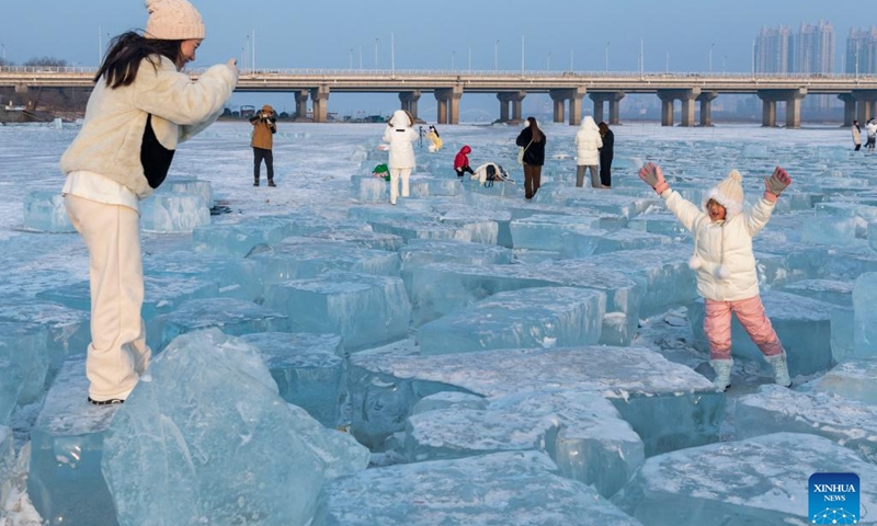 A child poses for photos with ice cubes at a section of Songhuajiang River in Harbin, northeast China's Heilongjiang Province on Feb. 1, 2023. This section of frozen river used to be the source of natural ice for installations at the Harbin Ice and Snow World. Some giant ice cubes were cut out but left there unused.(Photo: Xinhua)