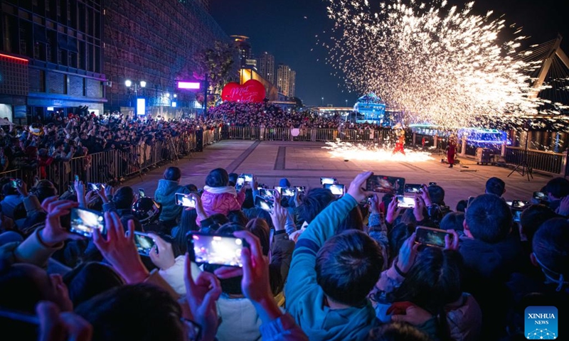 People watch iron flowers, a performance of splashing molten iron to create fireworks, at Laowaitan, a signature pedestrian street in Ningbo, east China's Zhejiang Province, Feb. 15, 2023. As the temperature gradually rises, a series of activities such as night market and iron flowers are held at Laowaitan to enrich the night life of citizens and tourists.(Photo: Xinhua)