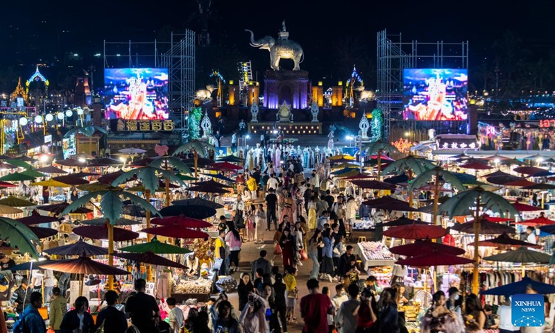 This photo taken on Feb. 12, 2023 shows a night fair in Jinghong City of Xishuangbanna Dai Autonomous Prefecture, southwest China's Yunnan Province. The night fair here has attracted a good many tourists, some of whom enjoyed a travel photo service in which photo studios provided traditional costumes and makeup to tourists.(Photo: Xinhua)