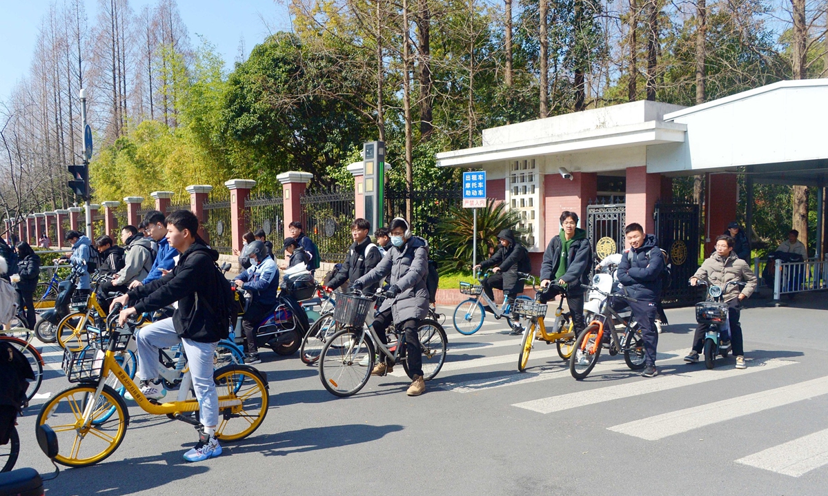 Students ride bicycles to take classes on the first day of the new semester in Fudan University in Shanghai on February 20, 2023. Photo: VCG