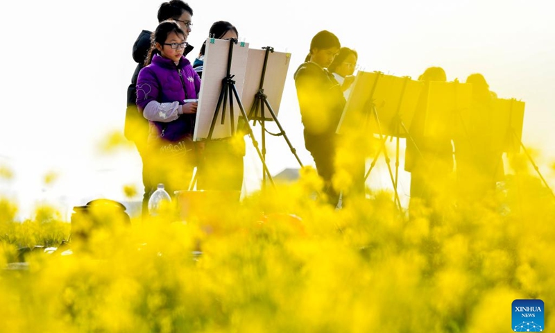 Students draw pictures near a cole flower field in Guanhu Village, Zhangshu City of east China's Jiangxi Province, Feb. 21, 2023.(Photo: Xinhua)