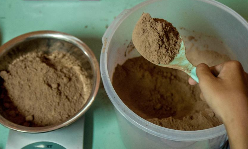 A worker weighs cocoa powder at Griya Cokelat Nglanggeran, a local chocolate production and souvenirs center in the village of Nglanggeran, Gunung Kidul district, Yogyakarta, Indonesia, Feb. 25, 2023. (Photo by Agung Supriyanto/Xinhua)