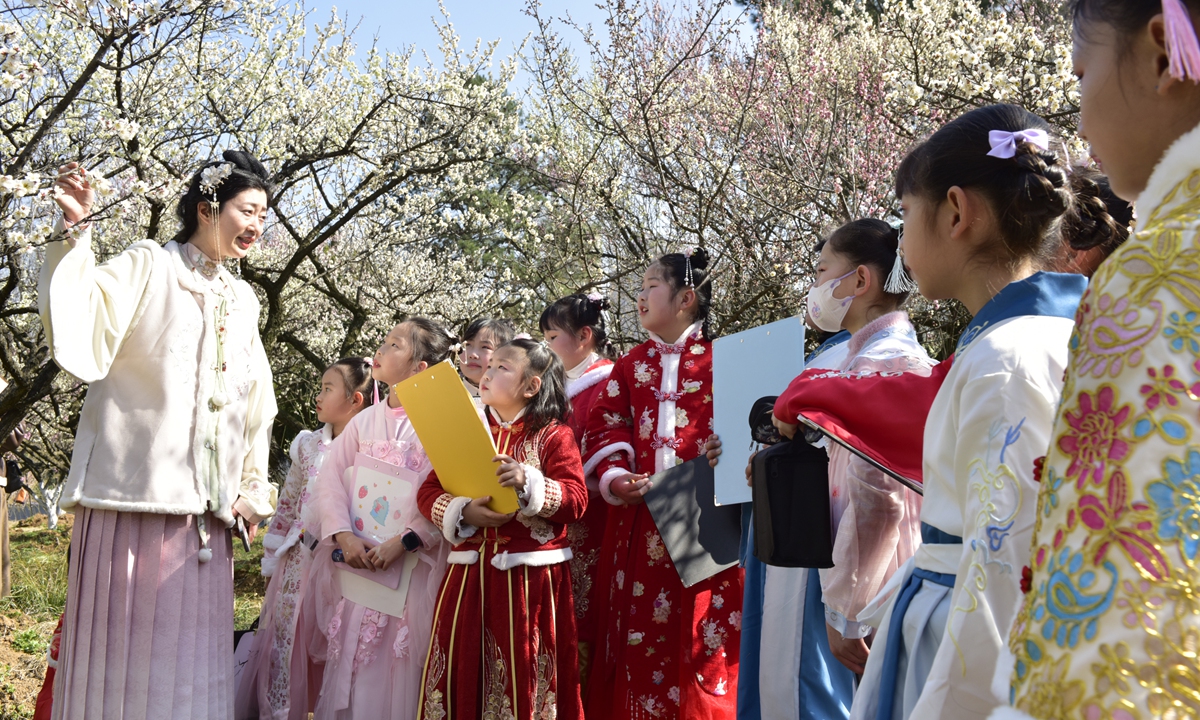 A teacher gives a speech on plum blossoms to a group of students dressed in Hanfu, a type of traditional Chinese clothing, in the Hefei Botanical Garden in Hefei, East China's Anhui Province, on February 27, 2023 as spring approaches. There are around 5,000 plum trees of 160 varieties in the botanical garden, according to reports. Photo: VCG