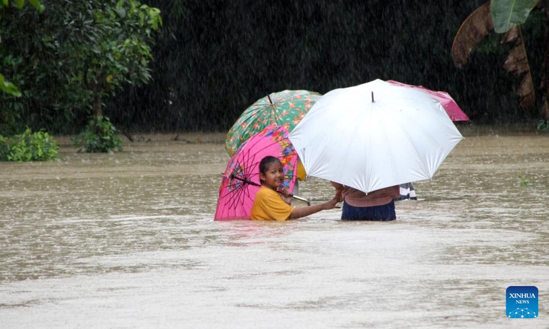 People wade through flood water after heavy rainfall and overflow of the Bengawan Solo River in Sragen, Central Java, Indonesia, March 2, 2023.(Photo: Xinhua)