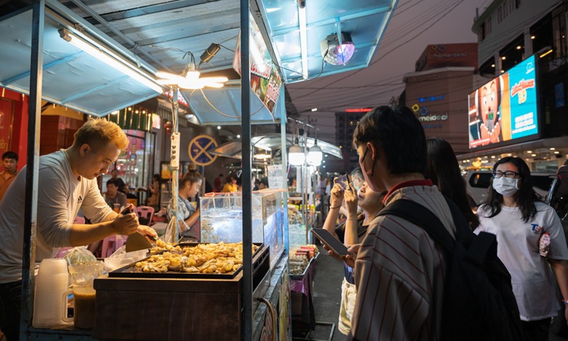 A vendor (L) prepares food at a night market in Vientiane, Laos on March 14, 2023.(Photo: Xinhua)