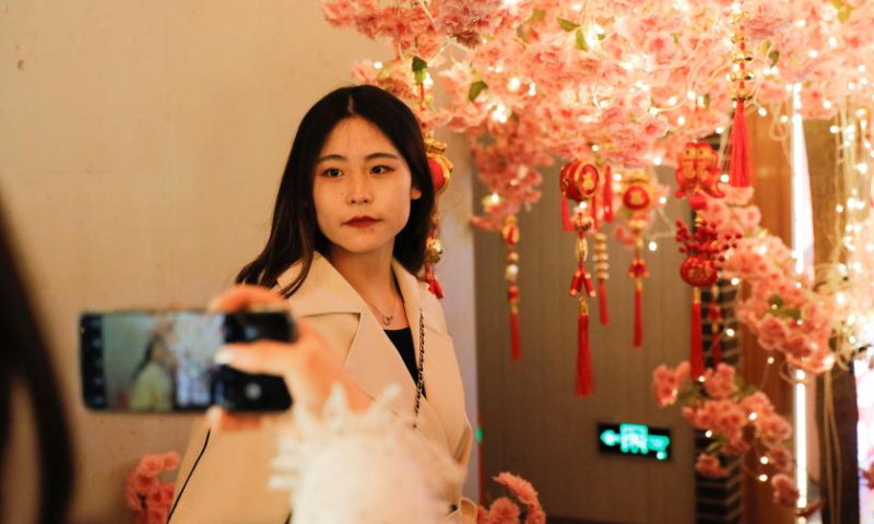 A visitor poses for photos at a night market in Lanzhou, northwest China's Gansu Province, March 25, 2023. Lanzhou has been continuously promoting its night economy and enriching night consumption forms. The recently-opened night market, featuring the Silk Road cuisine, song and dance, fashion and history, has become an attraction to lots of citizens and tourists. (Xinhua/Fang Xin)