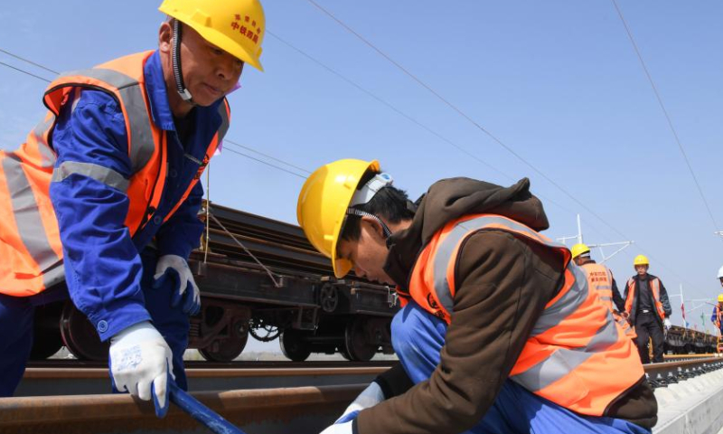 Staff members lay tracks on the Laixi-Rongcheng high-speed railway in Laixi, east China's Shandong Province, April 1, 2023. With a designed speed of 350 kilometers per hour, the Laixi-Rongcheng high-speed railway links cities of Laixi and Rongcheng in Shandong. The construction of the line officially entered track-laying phase here Saturday. (Xinhua/Zhu Zheng)