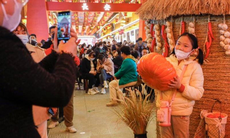 A girl poses for photos at a night market in Lanzhou, northwest China's Gansu Province, March 25, 2023. Lanzhou has been continuously promoting its night economy and enriching night consumption forms. The recently-opened night market, featuring the Silk Road cuisine, song and dance, fashion and history, has become an attraction to lots of citizens and tourists. (Xinhua/Fang Xin)