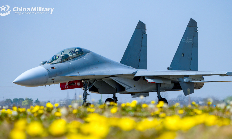 A fighter jet attached to an aviation brigade of the air force under the PLA Eastern Theater Command flies over blossoms of spring flowers and taxies on the runway after completing flight training recently. (eng.chinamil.com.cn/Photo by Li Jiguang)