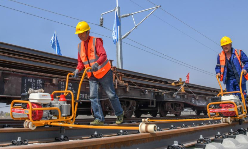 Staff members lay tracks on the Laixi-Rongcheng high-speed railway in Laixi, east China's Shandong Province, April 1, 2023. With a designed speed of 350 kilometers per hour, the Laixi-Rongcheng high-speed railway links cities of Laixi and Rongcheng in Shandong. The construction of the line officially entered track-laying phase here Saturday. (Xinhua/Zhu Zheng)