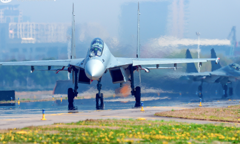 Fighter jets attached to an aviation brigade of the air force under the PLA Eastern Theater Command taxi on the runway flanked by yellow spring flowers before taking off for flight training recently. (eng.chinamil.com.cn/Photo by Li Jiguang)