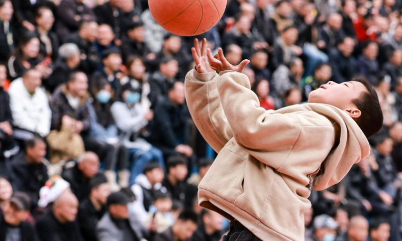 A kid plays basketball in Taipan Village, Taijiang County, southwest China's Guizhou Province, March 25, 2023. Village Basketball Association or Village BA, is a grassroot basketball tournament held in Taipan Village. Organized by local residents, this event has gained popularity over the years and draws a large crowd of spectators and participants alike. The tournament showcases the passion and skills of basketball players from rural areas, as they compete and demonstrate their teamwork on the court. (Xinhua/Ou Dongqu)