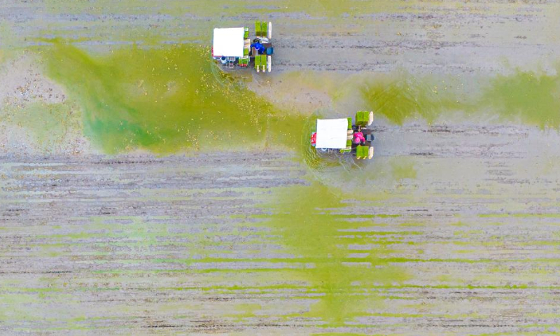 This aerial photo taken on April 4, 2023 shows farmers operating rice transplanters in the field in Chengnan Township of Wenling City, east China's Zhejiang Province. Around the time of Qingming Festival which falls on April 5 this year, farmers across the country are busy with farm work.(Xinhua/Xu Weijie)