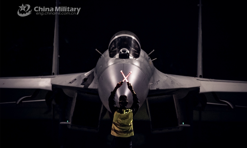 A ground crew member assigned to a naval aviation brigade under the PLA Southern Theater Command signals the pilot to taxi the fighter jet into the hangar during a day-and-night flight training exercise in early March, 2023. (eng.chinamil.com.cn/Photo by Fu Jinquan)