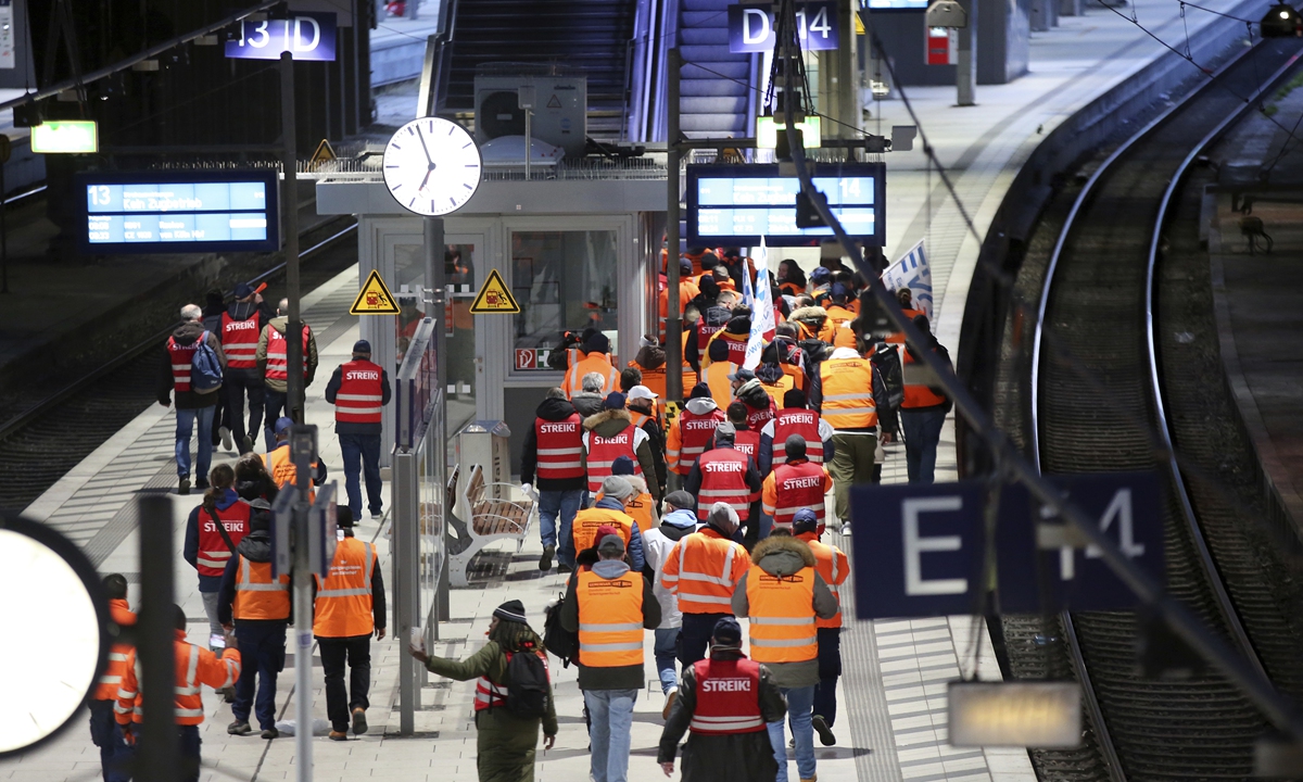Striking members of the EVG march with flags and strike vests through Hamburg's main train station on March 27, 2023. The trade union Verdi and the Railway and Transport Union (EVG) have called for a nationwide strike in the transport sector. Photo: VCG