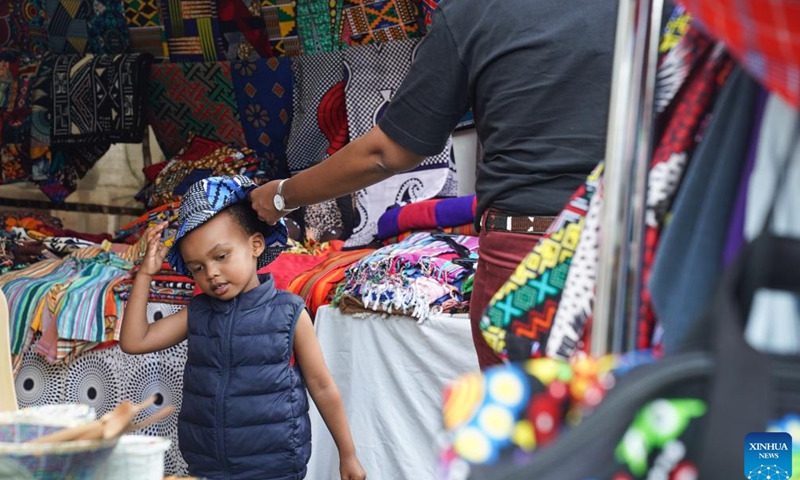 A shopper puts a hat on a child at an Easter market in Nairobi, Kenya, April 1, 2023. An Easter market is held here from April 1 to 2, which attracts lots of visitors. (Xinhua/Han Xu)