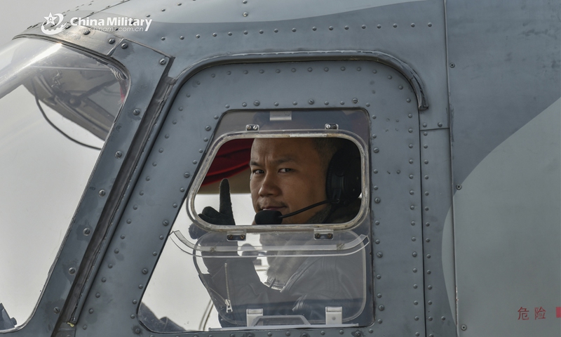 A pilot assigned to an air transport brigade under the PLA Air force's airborne troops signals to the ground crew during the intensive round-the-clock flight training recently. (eng.chinamil.com.cn/Photo by Li Zhuojun)