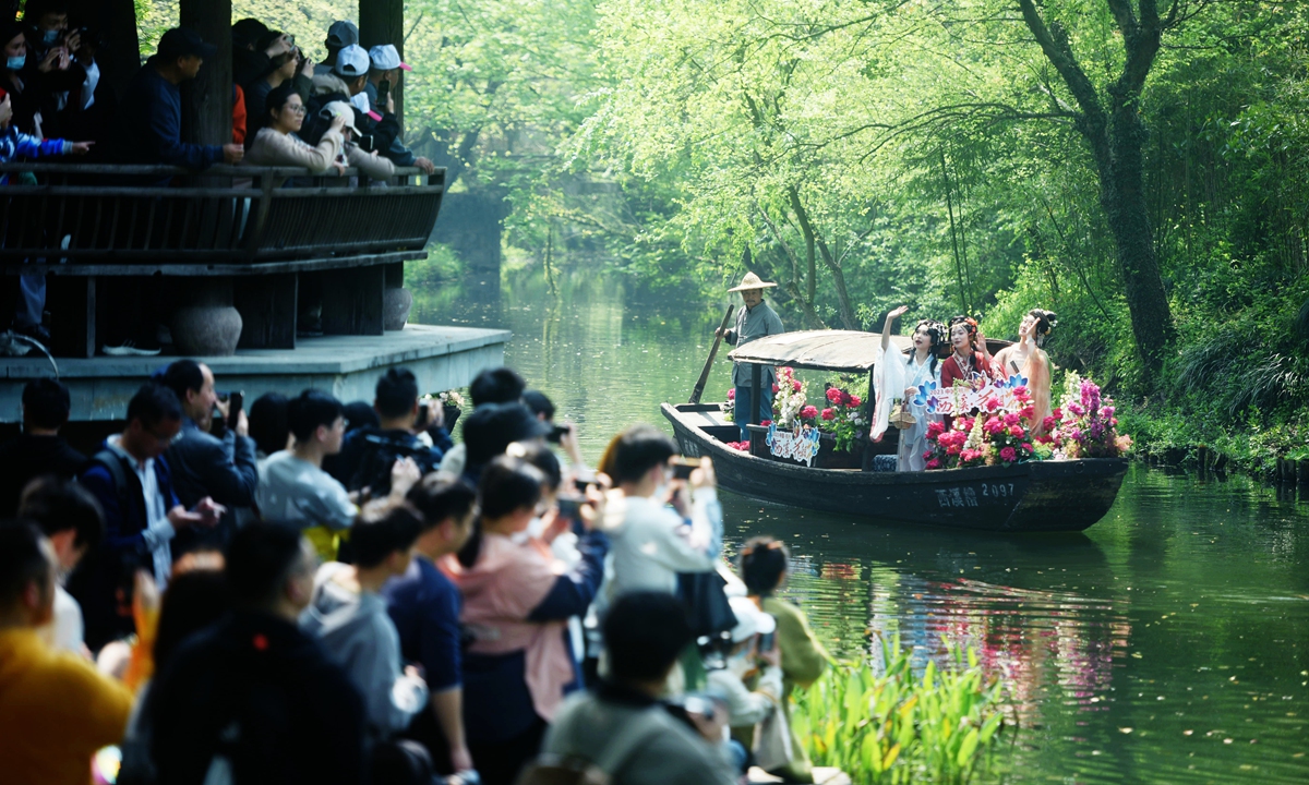 Twelve Flower Fairies, played by enthusiasts of Hanfu, or traditional Chinese outfits, wave their hands at tourists onshore during the Flower Fairies Festival on April 2, 2023, in Hangzhou, East China's Zhejiang Province. Photo: VCG