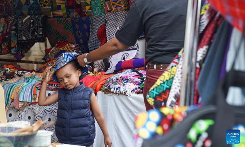 A shopper puts a hat on a child at an Easter market in Nairobi, Kenya, April 1, 2023. An Easter market is held here from April 1 to 2, which attracts lots of visitors.(Photo: Xinhua)