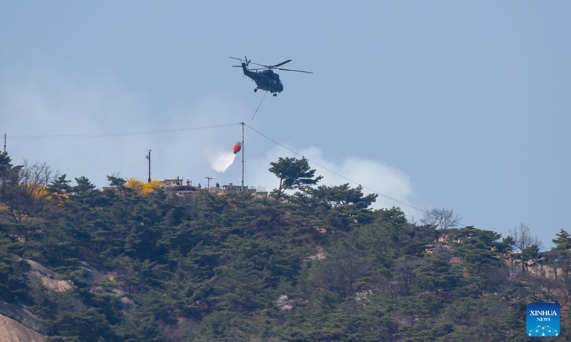 A helicopter tries to extinguish a forest fire on Mount Inwang in Seoul, South Korea, April 2, 2023. A relatively large fire occurred at 11:53 a.m. local time (0253 GMT) on Mount Inwang in Seoul, a mountain near the previous location of the country's presidential office. The firefighting authorities had tried to bring it under control for over three hours, mobilizing hundreds of officials, nine helicopters and other equipment. (Photo: Xinhua)