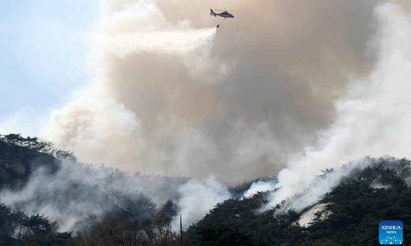 A helicopter tries to extinguish a forest fire on Mount Inwang in Seoul, South Korea, April 2, 2023. A relatively large fire occurred at 11:53 a.m. local time (0253 GMT) on Mount Inwang in Seoul, a mountain near the previous location of the country's presidential office.(Photo: Xinhua)