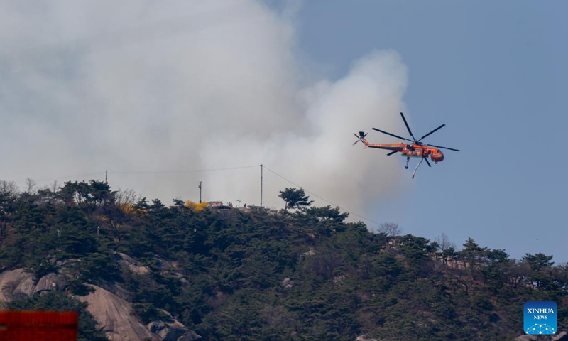 A helicopter tries to extinguish a forest fire on Mount Inwang in Seoul, South Korea, April 2, 2023. A relatively large fire occurred at 11:53 a.m. local time (0253 GMT) on Mount Inwang in Seoul, a mountain near the previous location of the country's presidential office.(Photo: Xinhua)