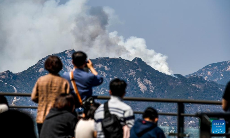 People look out for a forest fire on Mount Inwang in Seoul, South Korea, April 2, 2023. A relatively large fire occurred at 11:53 a.m. local time (0253 GMT) on Mount Inwang in Seoul, a mountain near the previous location of the country's presidential office.(Photo: Xinhua)