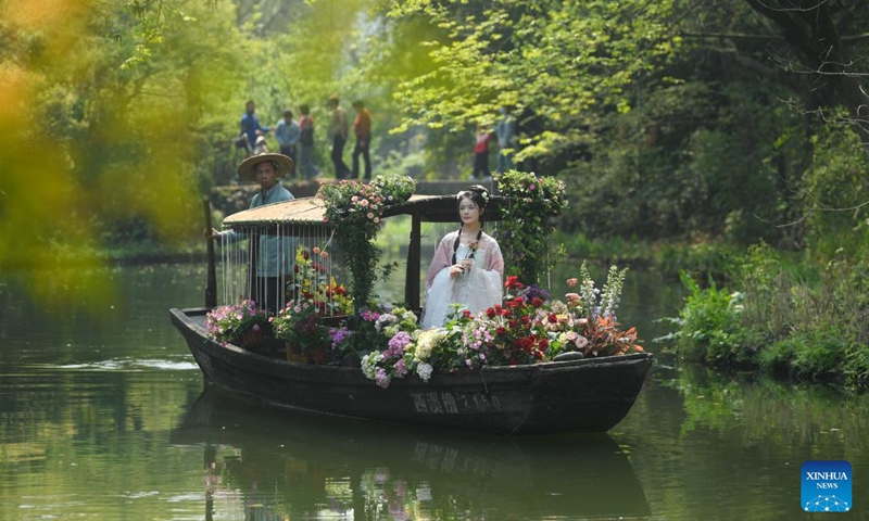 A young woman in traditional Chinese clothing Hanfu tours on a boat in Xixi Wetland in Hangzhou, capital of east China's Zhejiang Province, April 2, 2023. Lovers of traditional Chinese clothing Hanfu gathered here for a flower fairies festival to celebrate the coming of spring.(Photo: Xinhua)