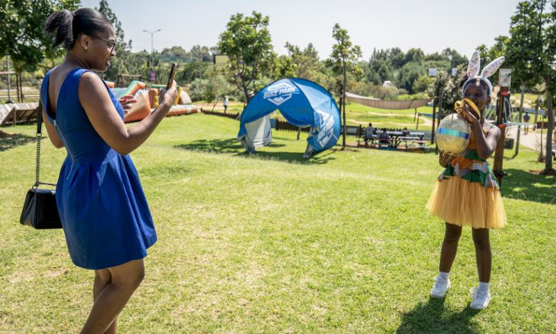 A girl poses for photos with a golden egg during an Easter egg hunting event at a park in Johannesburg, South Africa, April 8, 2023. Various activities were held in Johannesburg to mark the upcoming Easter. (Photo by Shiraaz Mohamed/Xinhua)