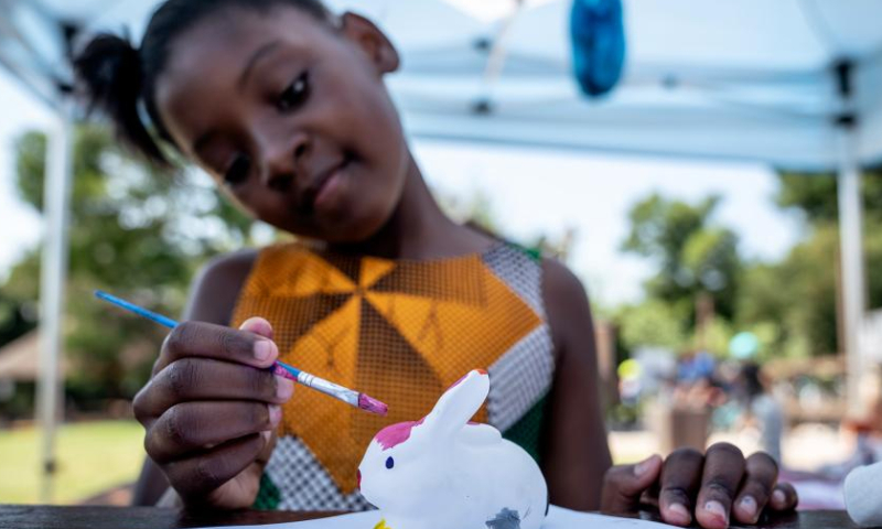 A girl paints a rabbit toy during an event to celebrate Easter at a park in Johannesburg, South Africa, April 8, 2023. Various activities were held in Johannesburg to mark the upcoming Easter. (Photo by Shiraaz Mohamed/Xinhua)