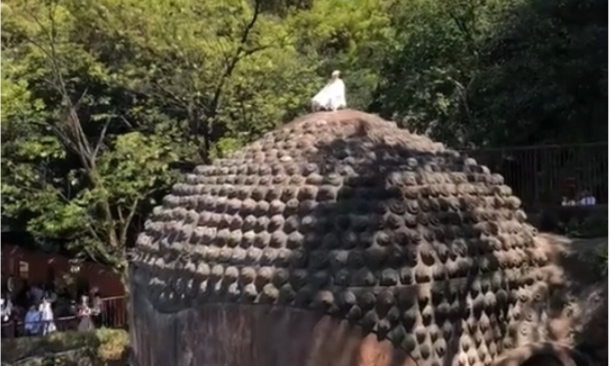 On Tuesday, a video of a tourist wearing white clothes climbing to the top of the statue’s head and meditating attracted attention in the scenic area.