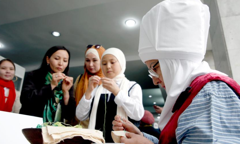 People learn embroidery from an artisan at an embroidery festival in Bishkek, Kyrgyzstan, April 15, 2023. An embroidery festival featuring Kyrgyz traditional embroideries was held here on Saturday. (Photo by Roman/Xinhua)