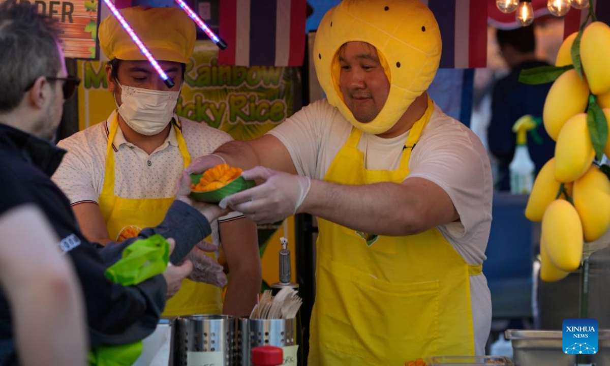 A food vendor hands over snacks to his customer at the Richmond Night Market in Richmond, British Columbia, Canada, on April 28, 2023. Photo:Xinhua