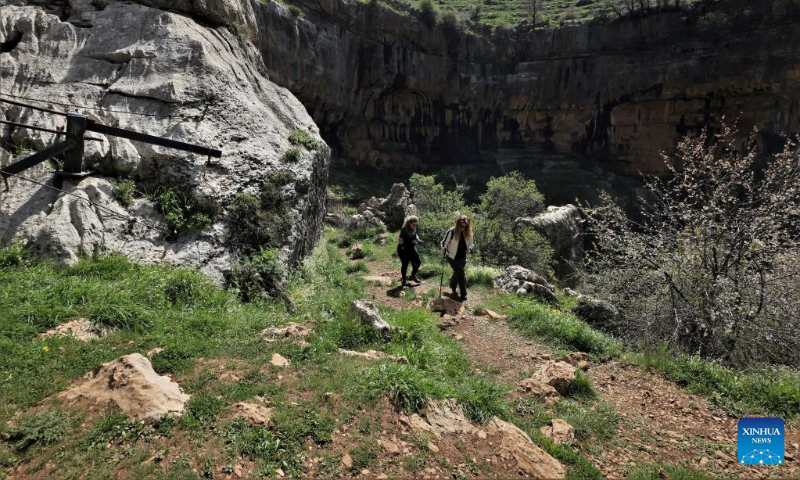 Two women go hiking in Baatara Pothole in the village of Balaa, Batroun District, Lebanon, April 23, 2023. Baatara Pothole, also known as Balaa Gorge, is located in the village of Balaa in Tannourine of Batroun district in Lebanon. (Xinhua/Liu Zongya)