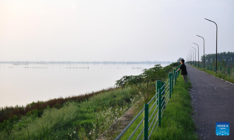 A person rests on a path along the Datong Lake in Yiyang, central China's Hunan Province, on April 20, 2023. Datong Lake, covering an area of 124,000 mu (about 8,266 hectares), was once heavily polluted due to disorderly aquaculture development. (Xinhua/Chen Zhenhai)
