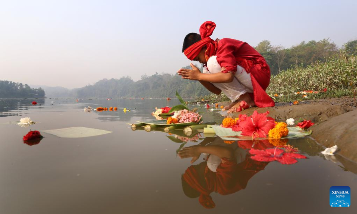 A boy prays before releasing floating flowers in a lake to celebrate the Boisabi festival in Chattogram, Bangladesh on April 12, 2023. With this festival, indigenous people in Chattogram Hill Tracts region bid farewell to the old year and welcome the new year. Photo:Xinhua