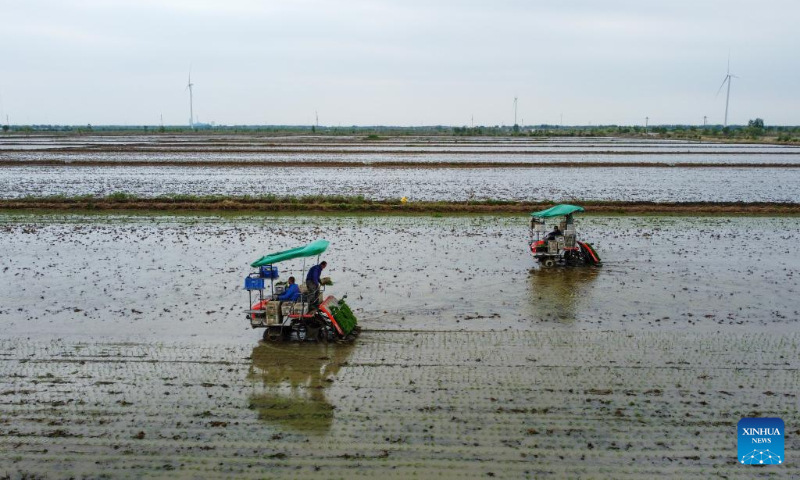 This aerial photo taken on May 5, 2023 shows farmers operating transplanters to transplant rice seedlings at an agricultural products development and demonstration center in north China's Tianjin. (Xinhua/Sun Fanyue)