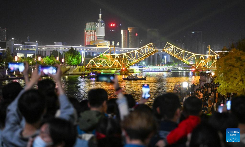 People take photos of the opened Jiefang Bridge in Tianjin, north China, May 1, 2023. The landmark bridge opened on Monday at a maximum angle of 60 degrees. (Xinhua/Sun Fanyue)