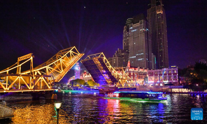 A boat sails past the opened Jiefang Bridge in Tianjin, north China, May 1, 2023. The landmark bridge opened on Monday at a maximum angle of 60 degrees. (Xinhua/Sun Fanyue)