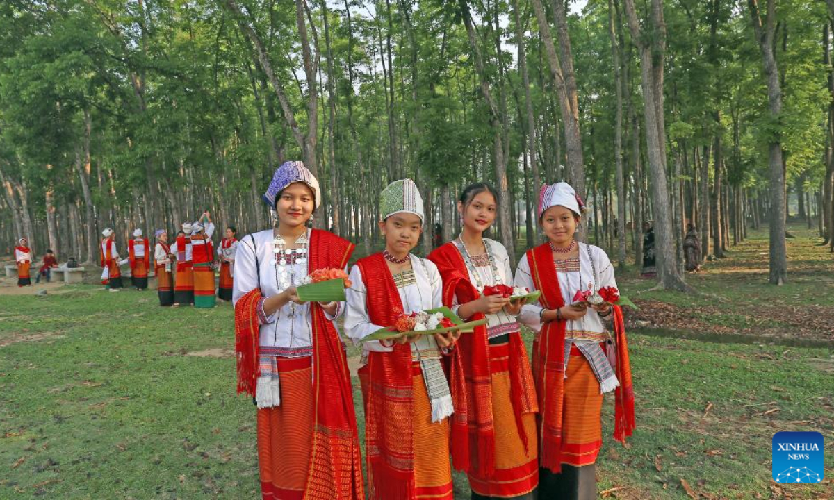 People wearing traditional dresses and holding flowers pose for photos during the celebration of the Boisabi festival in Chattogram, Bangladesh on April 12, 2023. With this festival, indigenous people in Chattogram Hill Tracts region bid farewell to the old year and welcome the new year. Photo:Xinhua