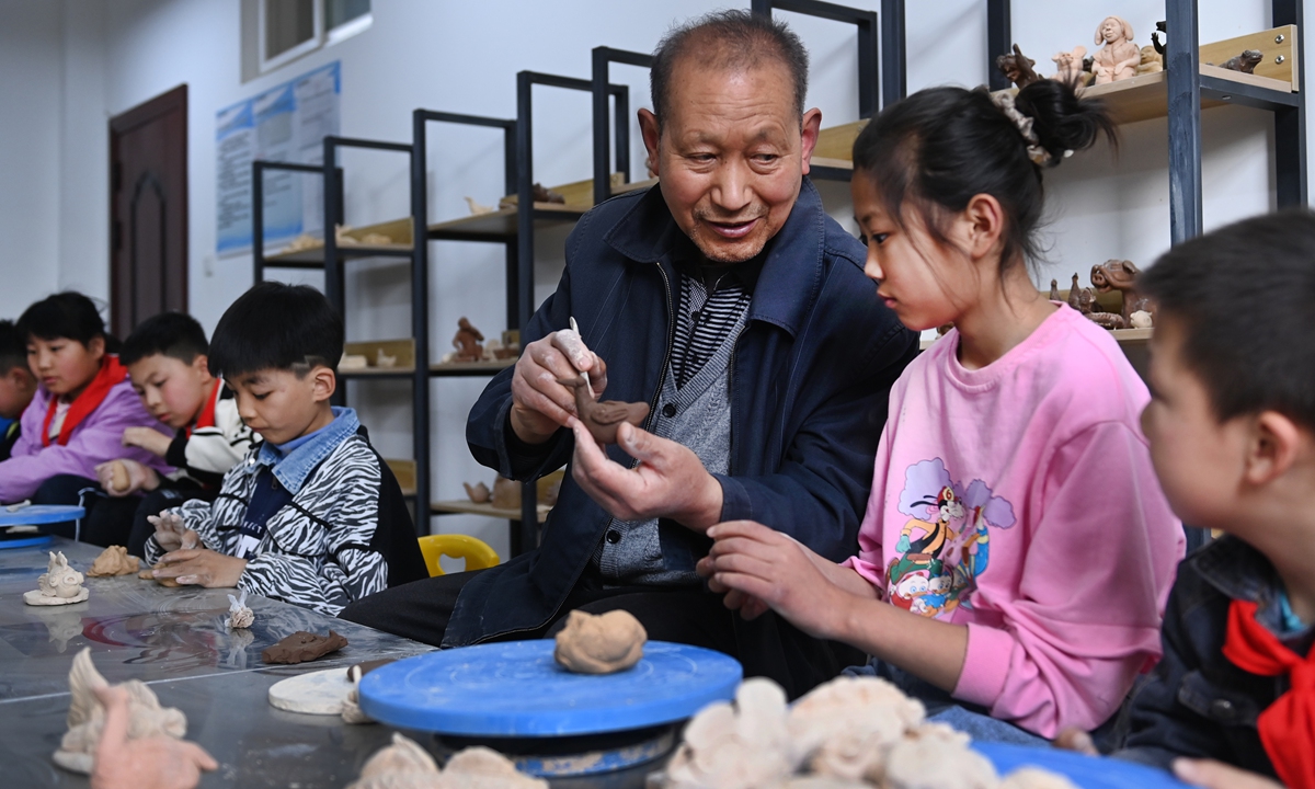 Miao Chunsheng (center) instructs primary school students on how to make clay sculptures in Xi'an, Northwest China's Shaanxi Province, on April 12, 2023. The 72-year-old Miao, a national intangible cultural heritage inheritor, has created more than 10,000 clay sculptures, most of which depict folk customs and labor production scenes from the 1950s to the early 1980s in the Guanzhong area in Shaanxi Province. Photo: VCG