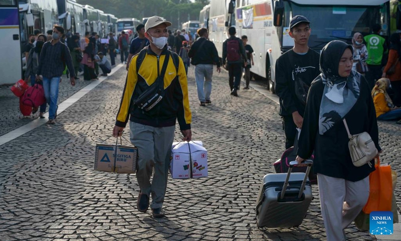 People carry belongings to board free-of-charge buses to their hometowns in Jakarta, Indonesia, April 17, 2023. Indonesia is facing the homecoming season when people from urban cities return to their respective hometowns to celebrate Eid with their families(Photo: Xinhua)