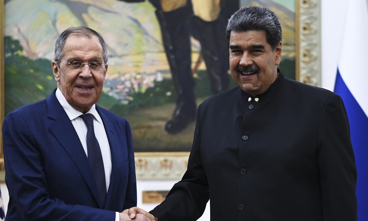 Russian Foreign Minister Sergei Lavrov (left) and Venezuelan President Nicolas Maduro shake hands during a meeting at the Miraflores Presidential Palace in Caracas on April 18, 2023. Lavrov called for like-minded countries to 