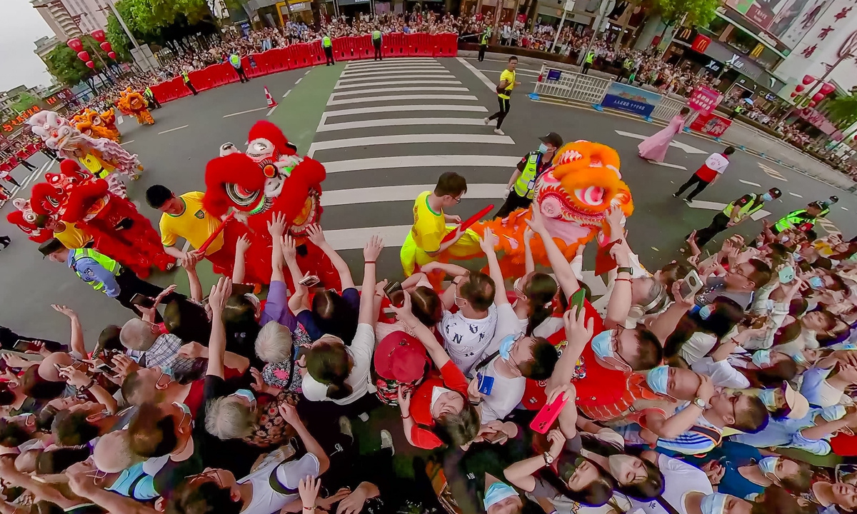 People in Foshan, South China's Guangdong Province reach out to the lion dance team during the traditional Double-Third Festival parade on the third day of the third lunar month on April 22, 2023. Photo: VCG