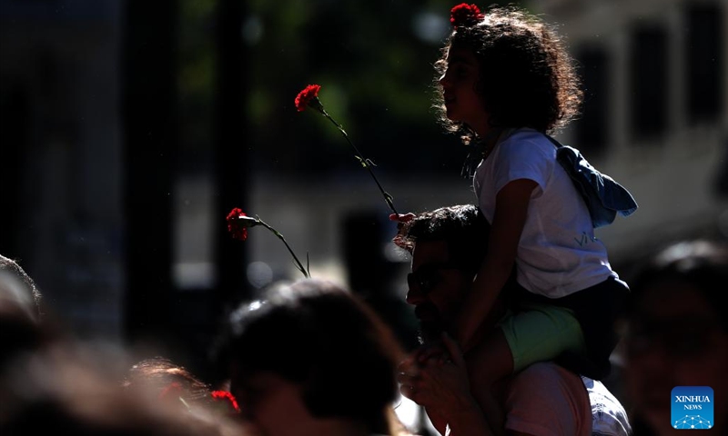 People holding red carnations take part in a parade to mark the 49th anniversary of the Carnation Revolution in Lisbon, Portugal, on April 25, 2023.(Photo: Xinhua)