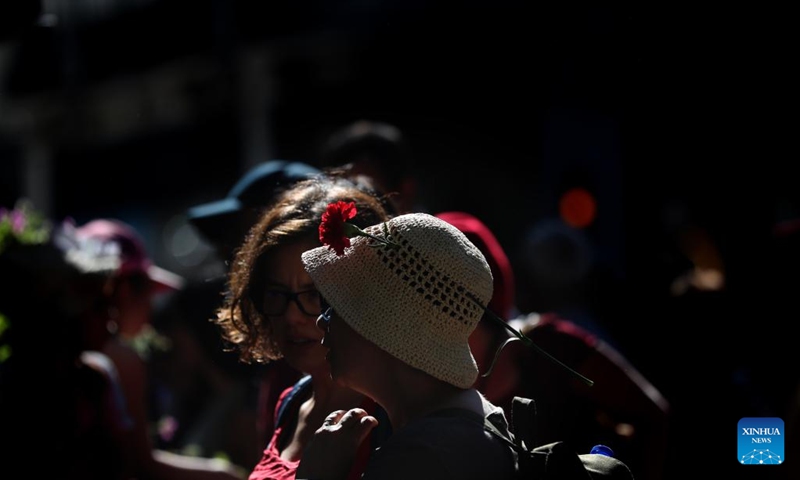 A woman with a red carnation on her hat takes part in a parade to mark the 49th anniversary of the Carnation Revolution in Lisbon, Portugal, on April 25, 2023.(Photo: Xinhua)