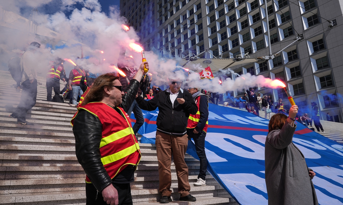 Members of the French Confederation of Labor union hold lit flares during a demonstration against pension reform in the La Defense business district of Paris, on May 3, 2023. French President Emmanuel Macron's government called for a crackdown on violent protesters as labor unions vowed to pursue their campaign against his pension reforms with a 14th day of demonstrations. Photo: VCG