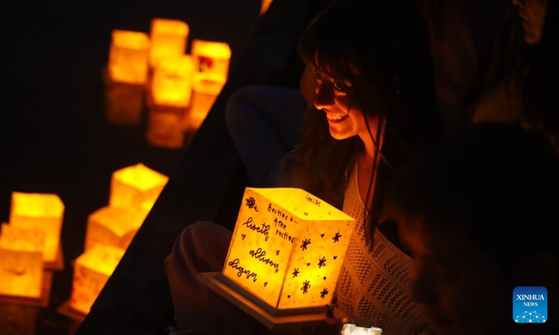 A woman waits to set afloat her lantern during the Water Lantern Festival held in Houston, Texas, the United States, May 27, 2023. (Xinhua/Xu Jianmei)